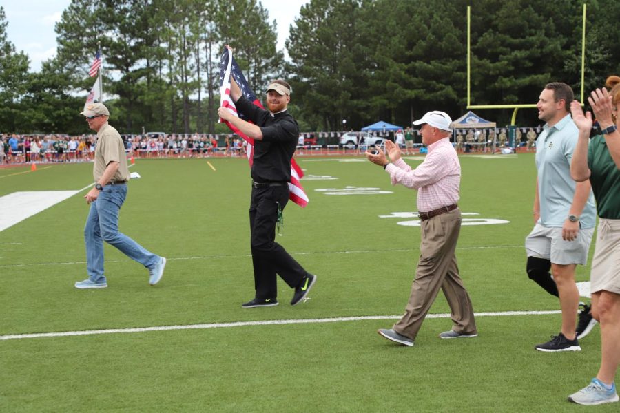 Fr.+Paul+emerges+from+a+helicopter%2C+proudly+waving+the+American+flag+at+the+start+of+the+Patriotism+Bowl.